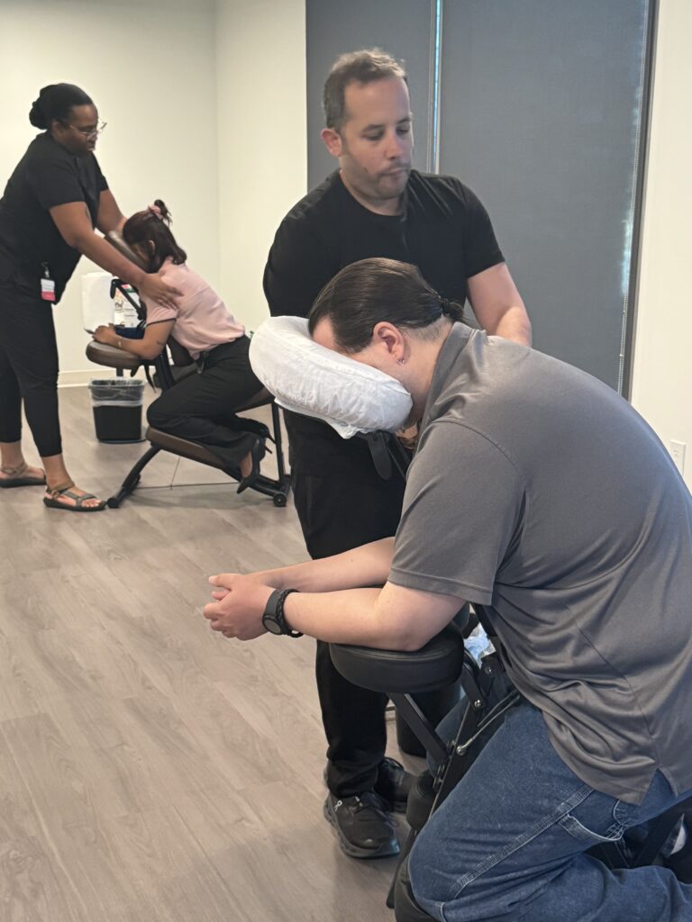 A seated man with a thoughtful expression, while another man stands behind him, creating a dynamic interaction.