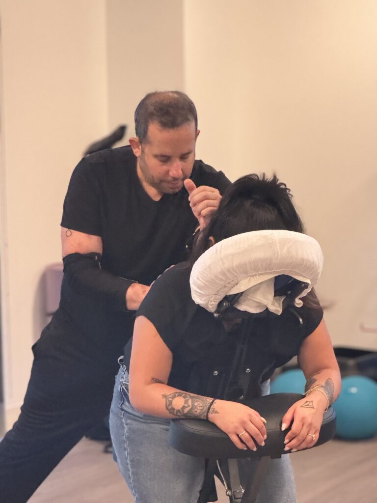 A man receives a haircut from a woman, symbolizing personal grooming and self-care in a professional environment.