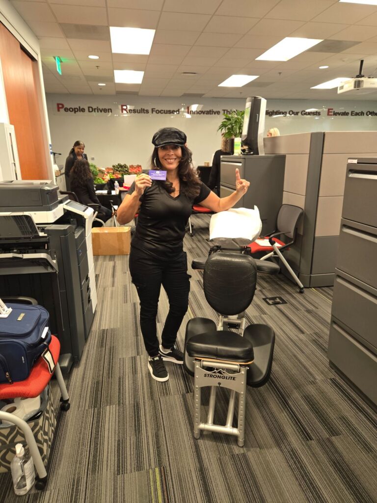 A woman seated at a desk in an office, working on a computer, surrounded by a professional environment.