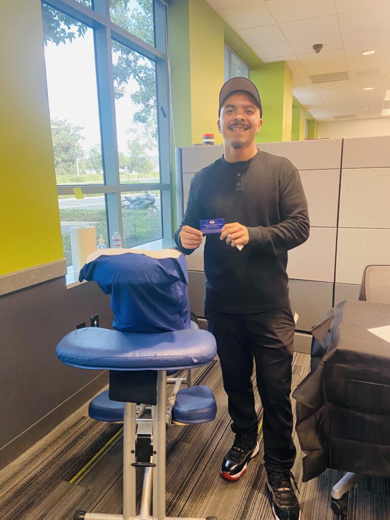 A man stands beside a chair, holding a blue plate, symbolizing thoughtful holiday gifts for employee well-being.