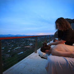 A woman enjoys a soothing massage on a balcony, with breathtaking mountain views providing a serene escape from daily stress.