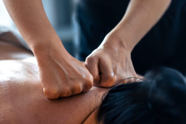 Masseur uses fist pressure technique on the back, providing deep relaxation, recovery, and a modern wellness vibe.